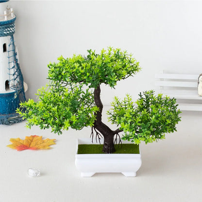 Artificial bonsai tree with rich green foliage and a curved dark brown trunk, placed in a sleek white pot on a light tabletop with nautical and seasonal décor accents—ideal for home styling, office greenery, and Japanese-inspired interior design.