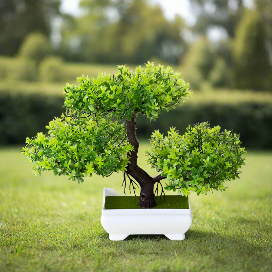 Realistic artificial bonsai tree with dense green foliage, a textured dark brown trunk, and a white ceramic planter, displayed outdoors on grass with a blurred garden background—perfect for indoor greenery, minimalist home décor, and zen-inspired styling.