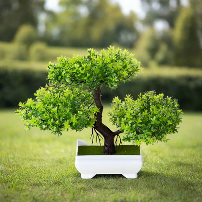 Realistic artificial bonsai tree with dense green foliage, a textured dark brown trunk, and a white ceramic planter, displayed outdoors on grass with a blurred garden background—perfect for indoor greenery, minimalist home décor, and zen-inspired styling.